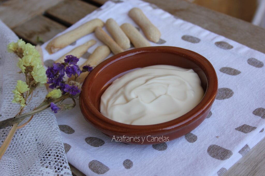 Receta de mayonesa casera clásica: cazuela de barro con mayonesa casera y unos roscos de pan. Un poco de flor de lavanda acompaña a la imagen.